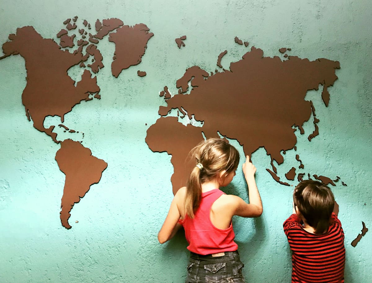 Niños señalando zonas en un mapa del mundo