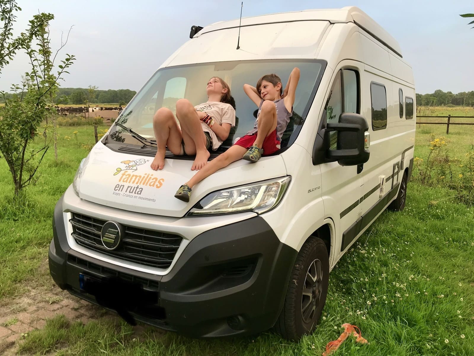 Niños sobre el capó de una furgoneta con el logotipo de Familias en Ruta